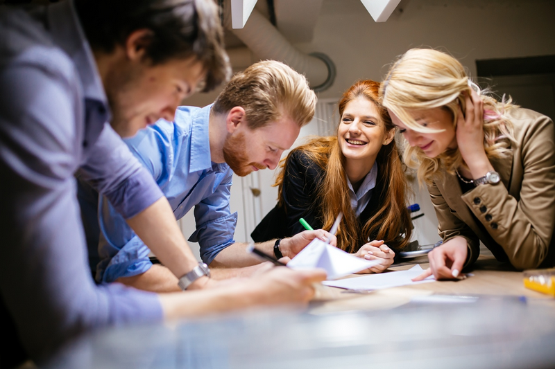 A group of people working together and smiling around a table.